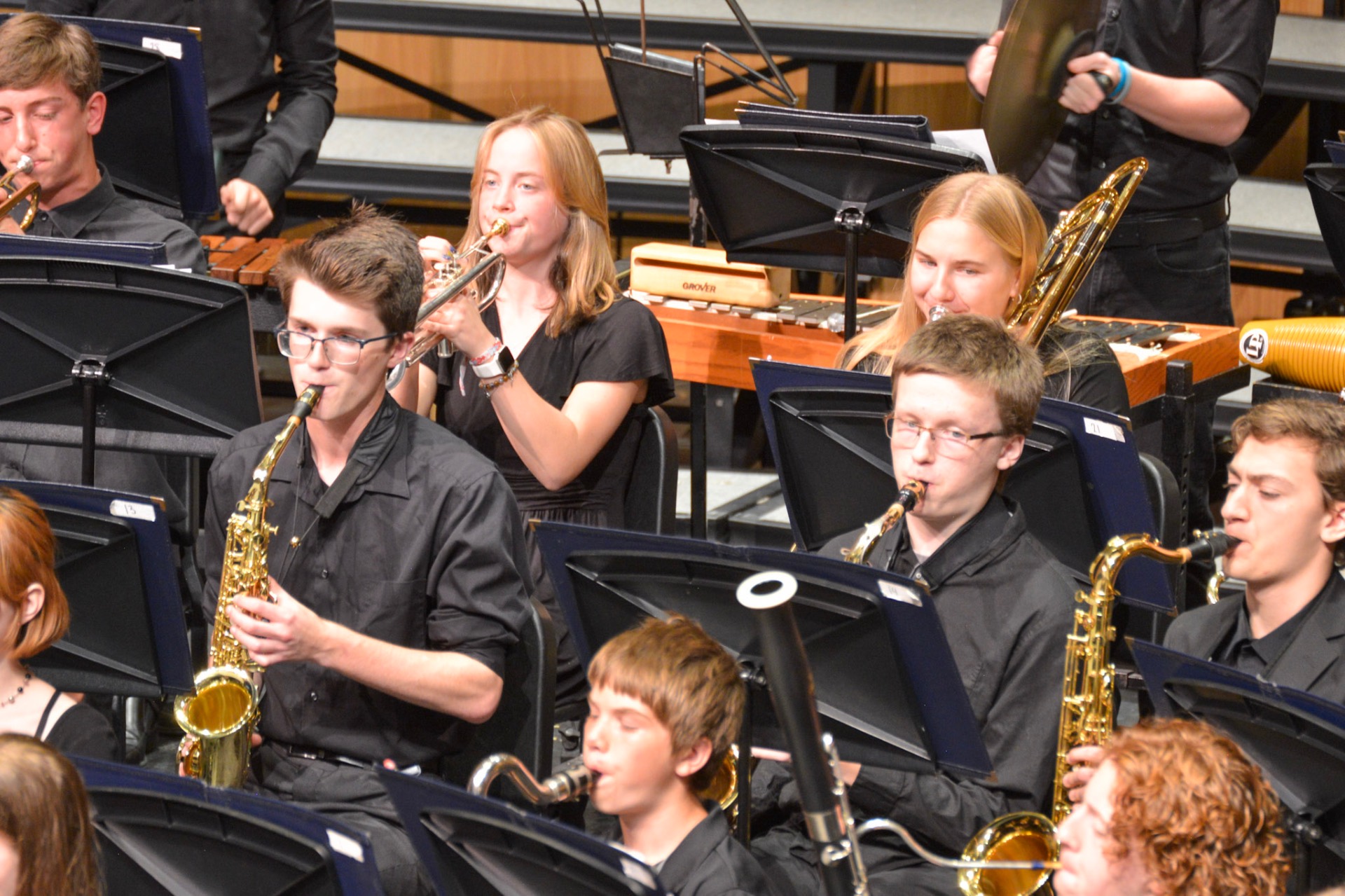 Concert band students playing saxophone, trumpet, and trombone
