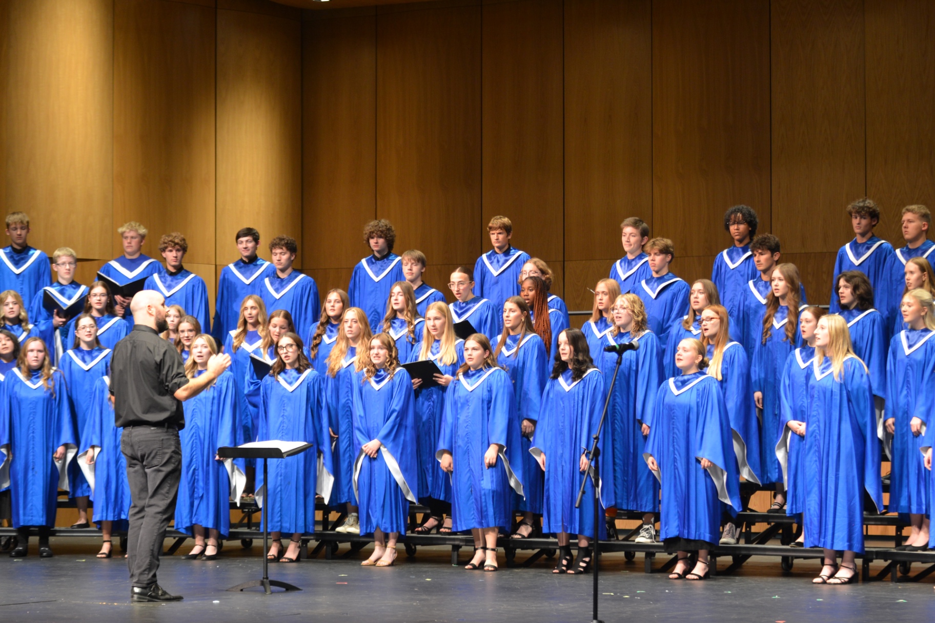 Sartell choir in blue robes performing with their director